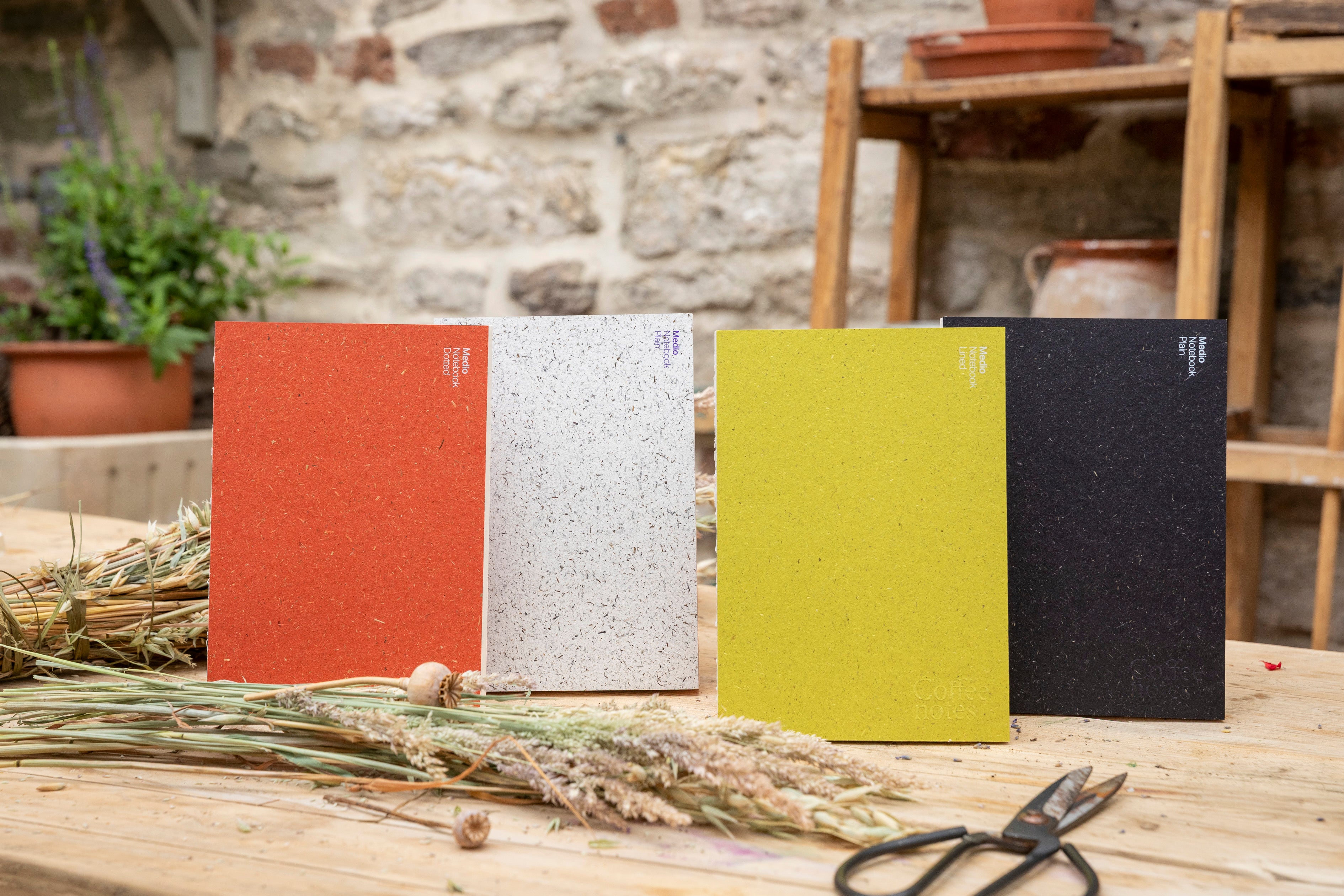Four notebooks in different colors on a wooden surface with a rustic background